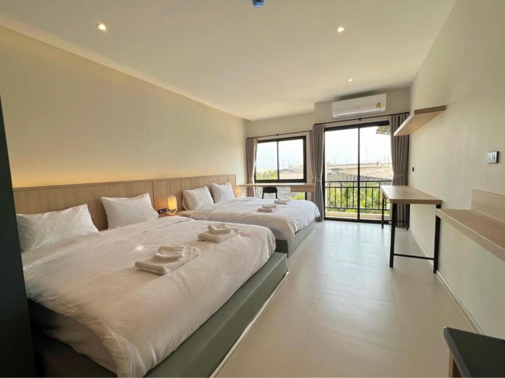 Ban Pak RaetにあるThe Way Hotel Ban Pongの大きな窓付きの客室で、ベッド2台が備わります。