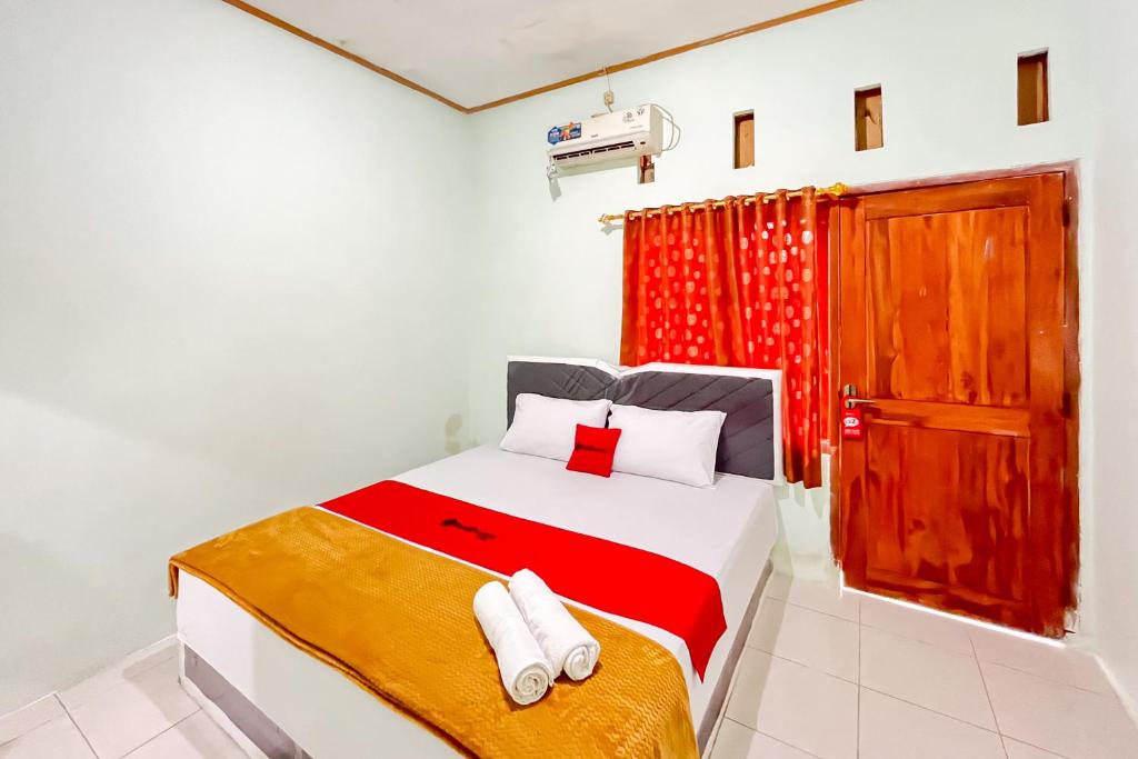 um quarto com uma cama e uma porta vermelha em RedDoorz Syariah near RS Bhayangkara Nganjuk em Nganjuk