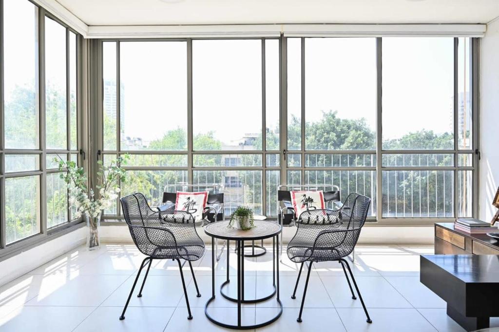 a room with a table and chairs and windows at Smiling Joe by HolyGuest in Tel Aviv