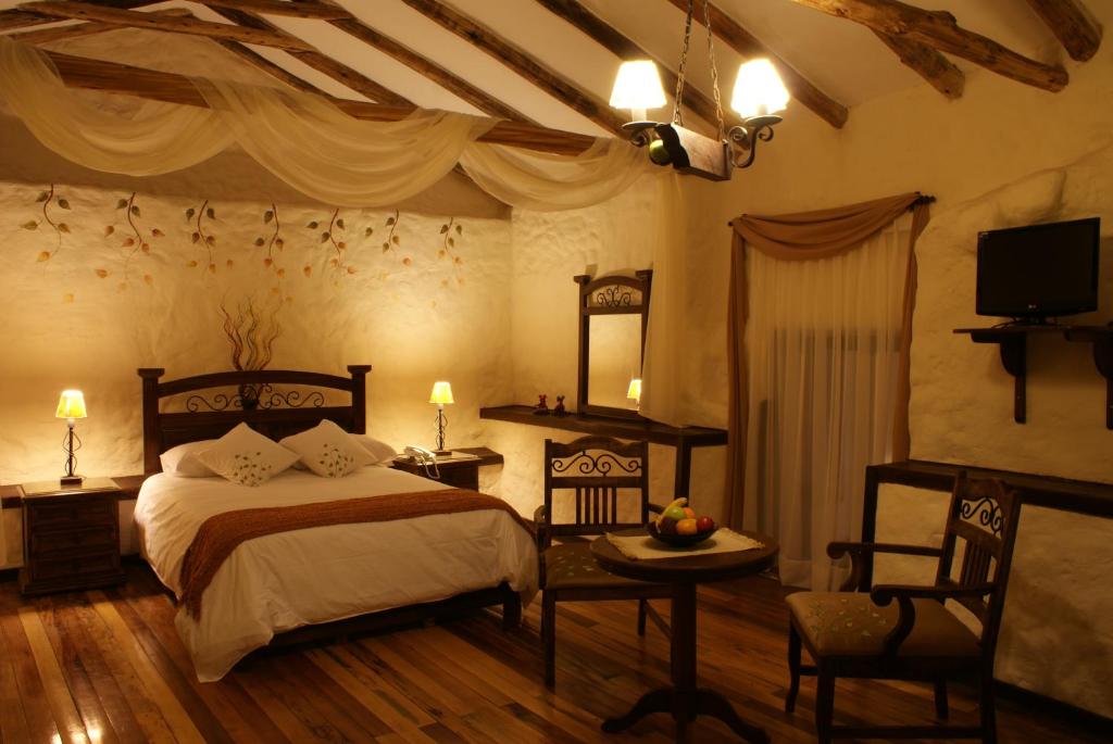 a bedroom with a bed and a table and a tv at Unaytambo Boutique Hotel Cusco in Cusco