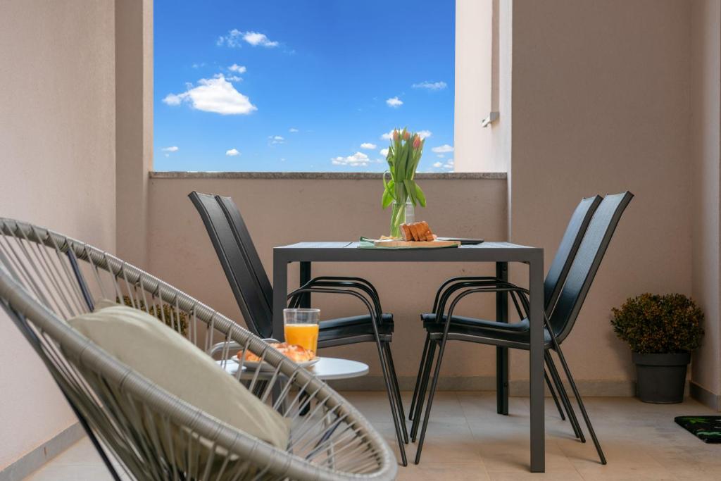 una mesa y sillas en un balcón con ventana en Green Nest, ground floor apt with garden & garage, en Medulin