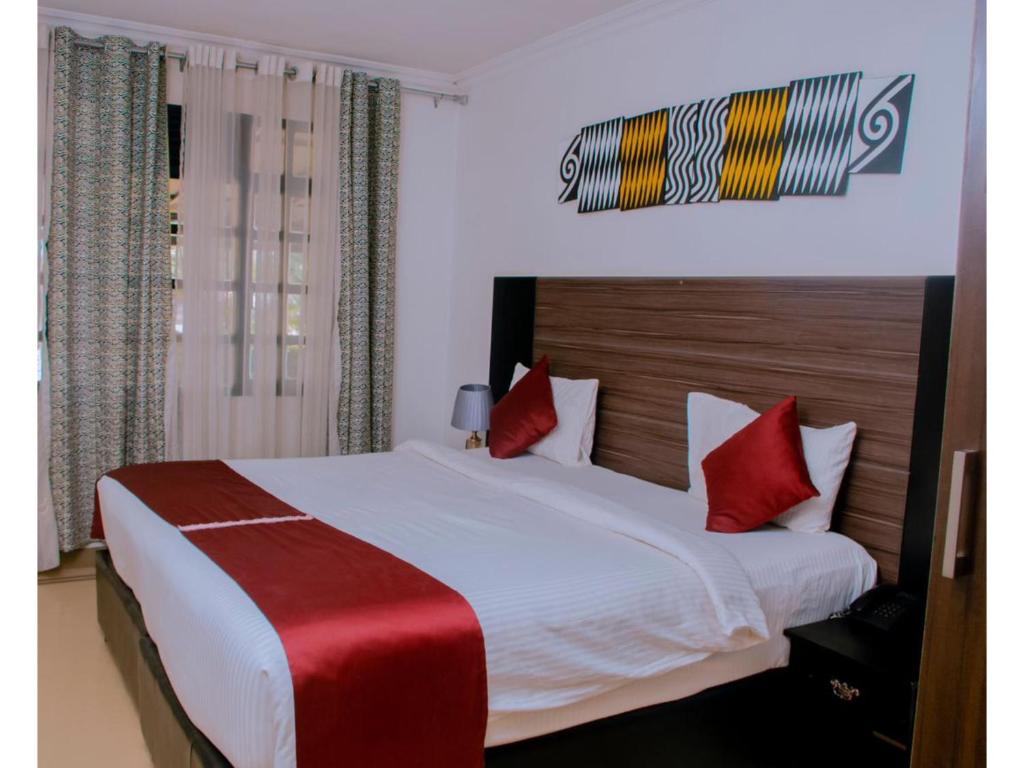 a bedroom with a large white bed with red pillows at Boutique Hotel Rwanda in Kigali