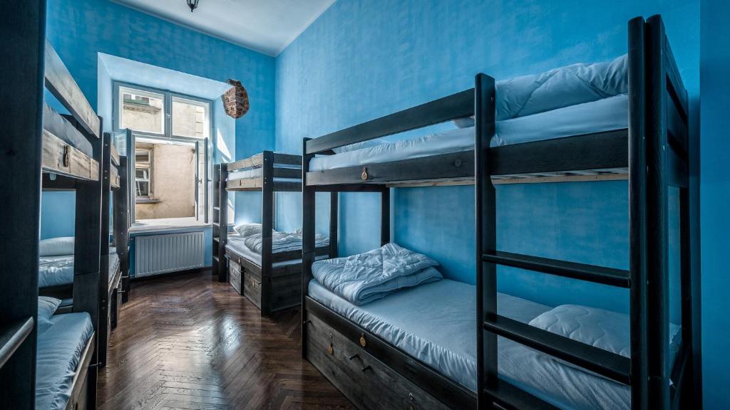 クラクフにあるザ リトル ハバナ パーティー ホステルの青い壁の客室で、二段ベッド3組が備わります。