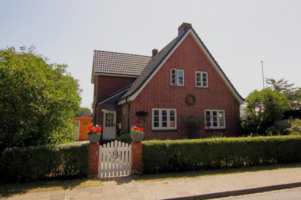 uma casa de tijolos vermelhos com uma cerca branca em Starklef 29_ Whg_ 2 em Wyk auf Föhr