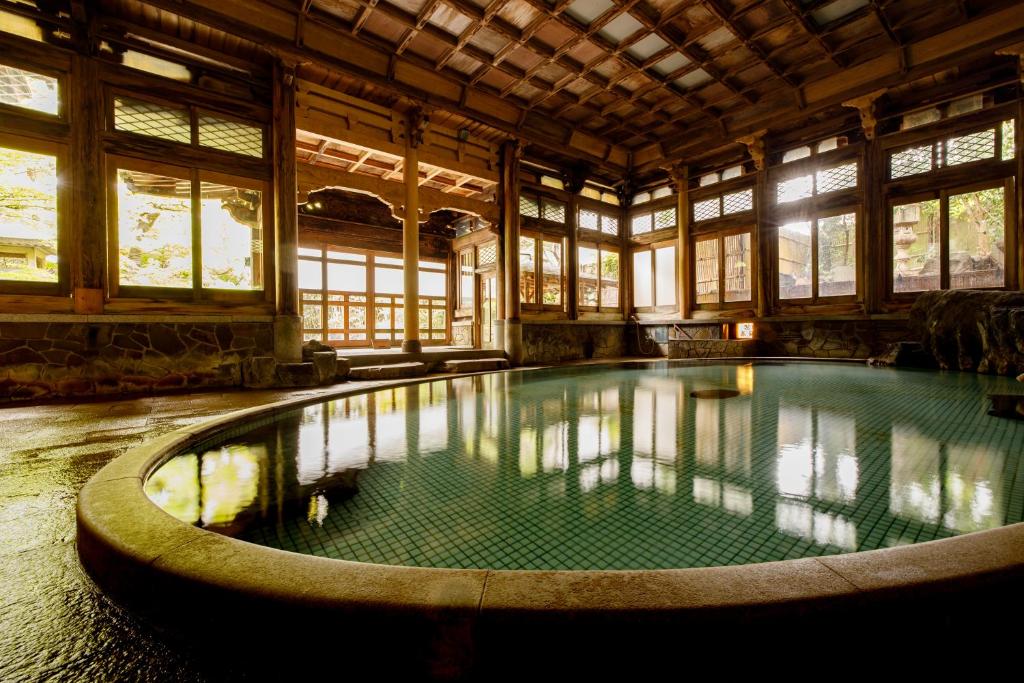 a large swimming pool in a building with windows at Shoraiso in Yamanouchi
