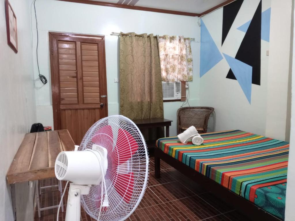 a room with a fan and a bed at ALFA Garden Lodge in El Nido