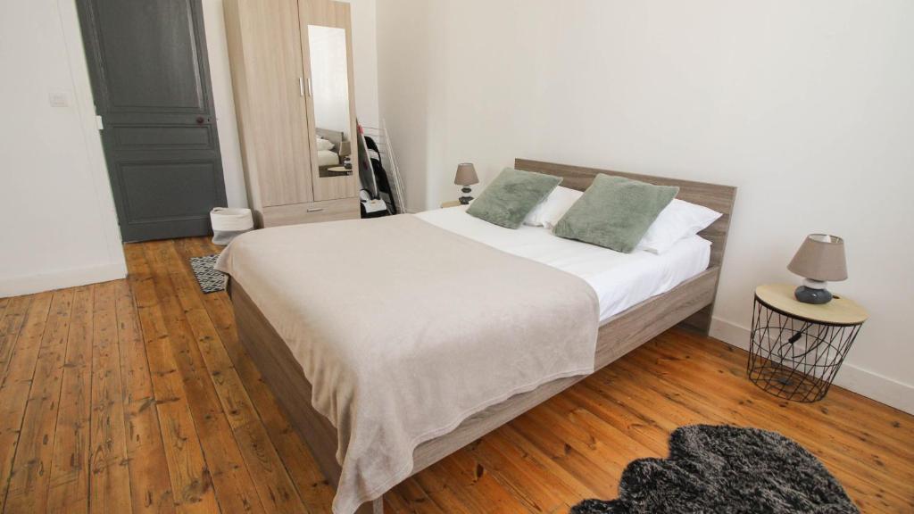 a bedroom with a bed with white sheets and green pillows at Residence Pasteur Angouleme in Angoulême