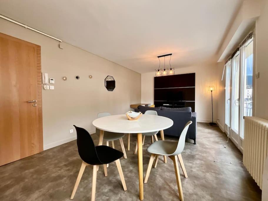 une salle à manger avec une table et des chaises blanches dans l'établissement Les Violettes, bel appartement au centre-ville, à Gérardmer