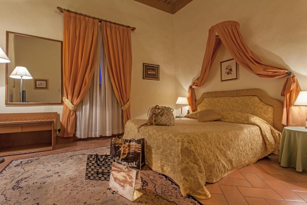 
a bedroom with a bed, a chair, and a lamp at Relais Il Chiostro Di Pienza in Pienza
