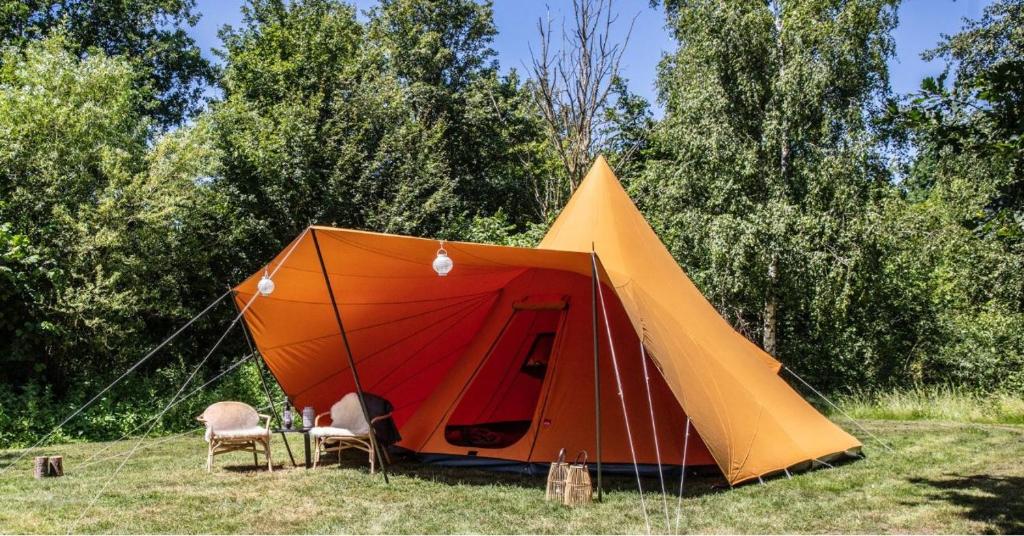 uma tenda laranja e laranja com cadeiras num campo em Ingerichte de Waard tent voor 2 personen em Zwiggelte