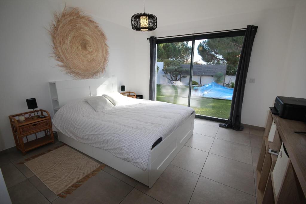 1 dormitorio con cama blanca y ventana grande en Belle villa contemporaine climatisee, piscine privee, 6 - 8 couchages, 3 chambres, wifi, à 3 km de la plage -LXDALI25B en Portiragnes