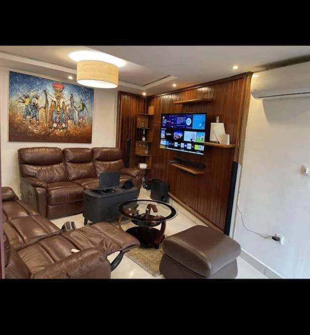 uma sala de estar com um sofá e uma televisão em Sterling House em Douala