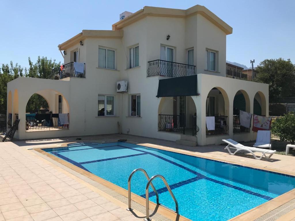 a villa with a swimming pool in front of a house at Villa Alsancak Girne in Karavas