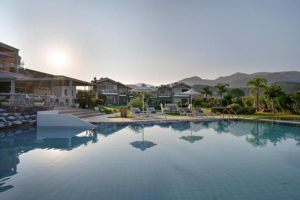 a swimming pool in a resort with mountains in the background at Restia Suites Exclusive Resort -Adults Only in Almiros Beach