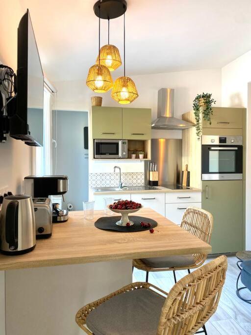 une cuisine avec une table en bois avec des chaises et un comptoir dans l'établissement Villa Maya - 3 Groussan - Avignon - CLIM - TERRASSE, à Avignon