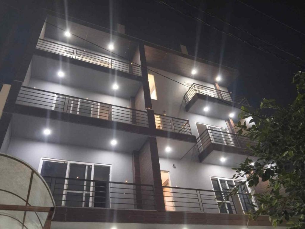a white building with balconies at night with lights at Happy Living in Noida