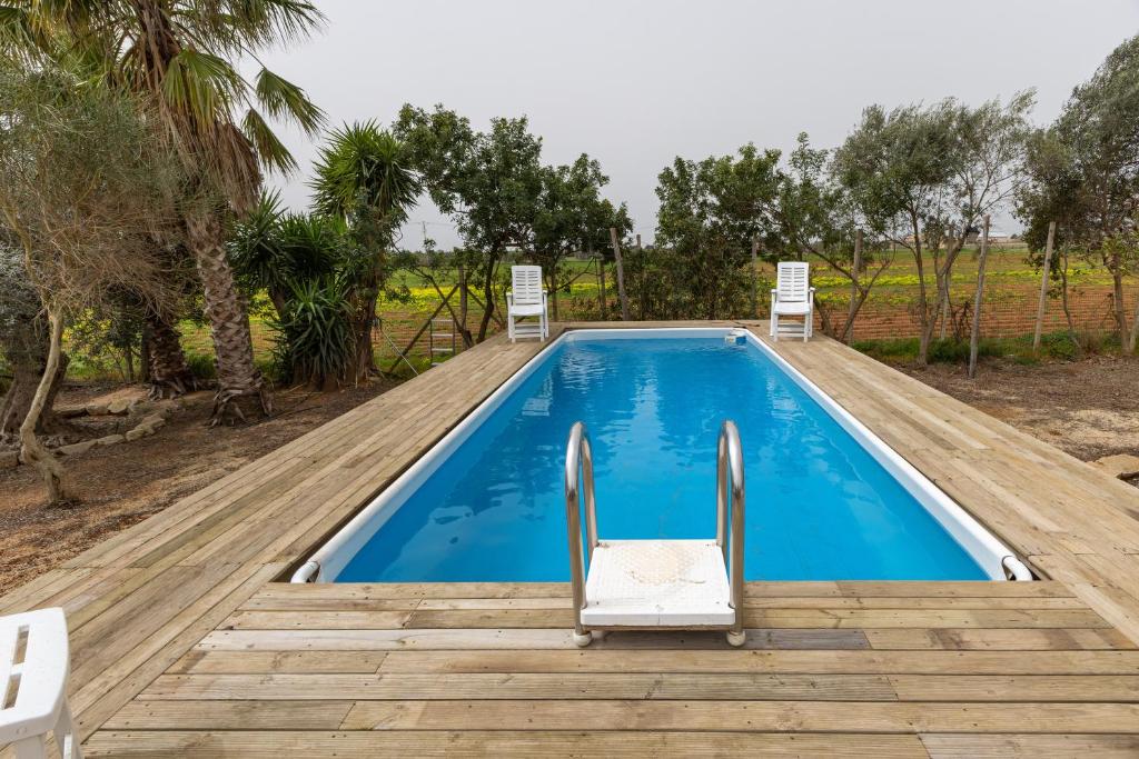 a swimming pool with chairs on a wooden deck at The Holiday And Art Seahorse House in Vittoria