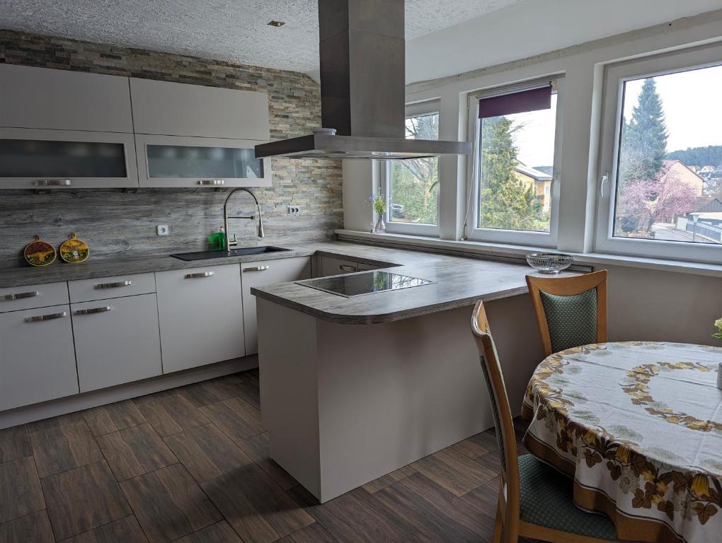 a kitchen with white cabinets and a table and a sink at Nepalaya Ferienwohnung in Pegnitz