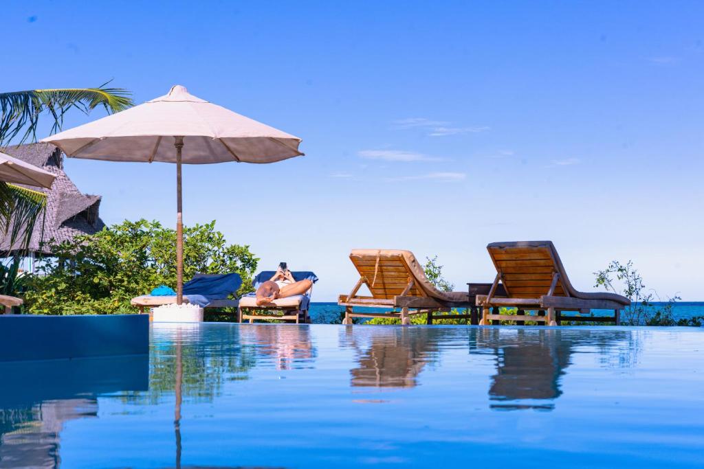 a person sitting in chairs and an umbrella next to a pool at Jafferji Beach Retreat, in Matemwe