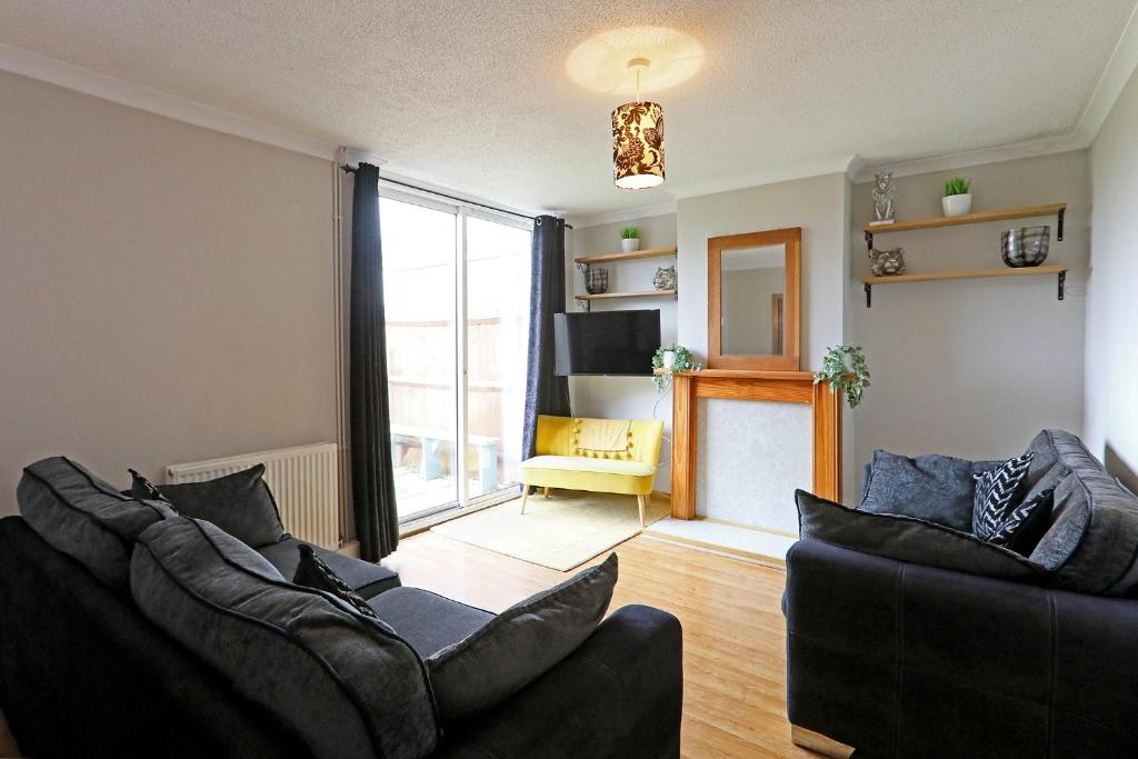 a living room with two couches and a large window at Lovely 3 bedroom house with free parking & garden in Norwich