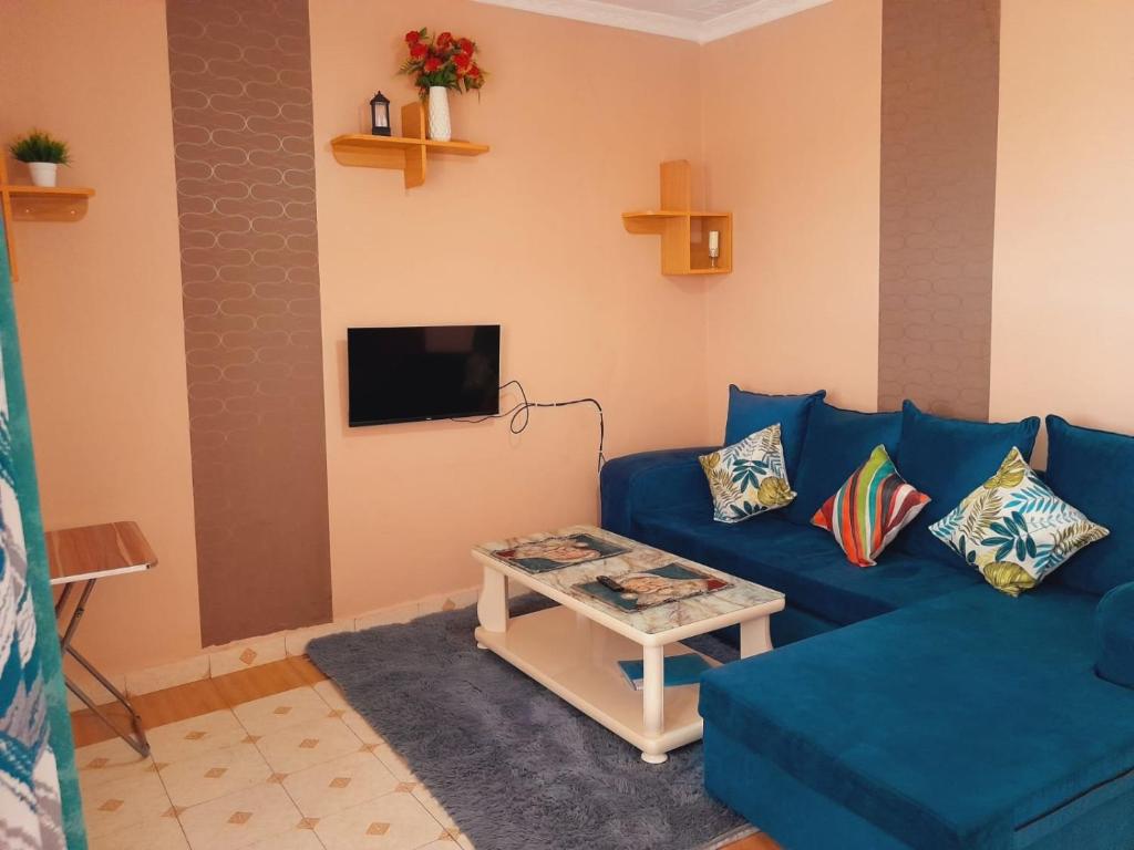 ein Wohnzimmer mit einem blauen Sofa und einem Tisch in der Unterkunft Hotfoot Homestays in Isiolo