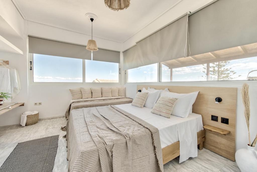 a bedroom with a large bed in a room with windows at Santa Maroma Rooms & Houses in Vasilikos