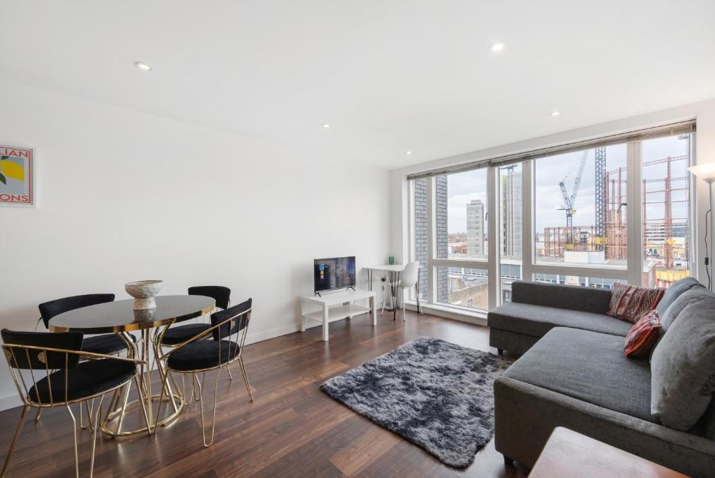 een woonkamer met een bank en een tafel bij Modern Shoreditch flat next to station with lift and views in Londen