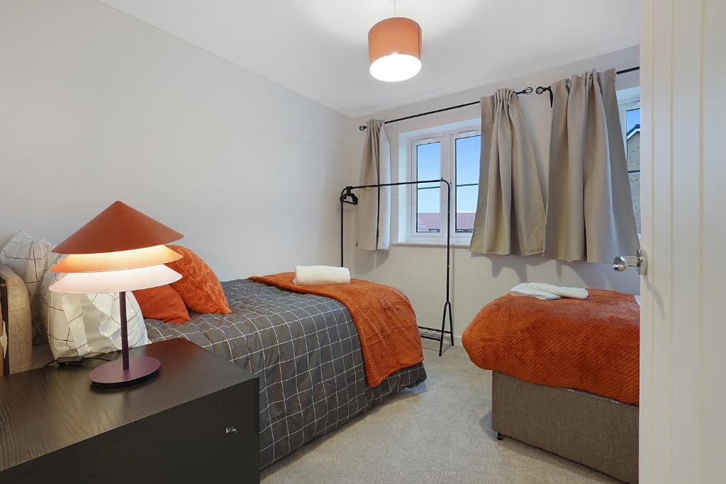 a bedroom with a bed and a lamp and a window at Gravesend 2 Bed Apartment-2 minutes walk from shops, Restaurants and Motorway. Sleep upto 5 in Northfleet