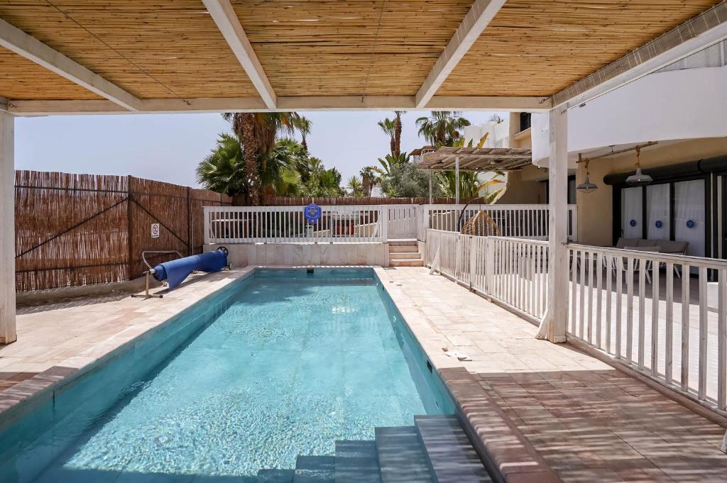una piscina cubierta con techo de madera y una piscina en YalaRent Cliff side villa with private pool en Eilat