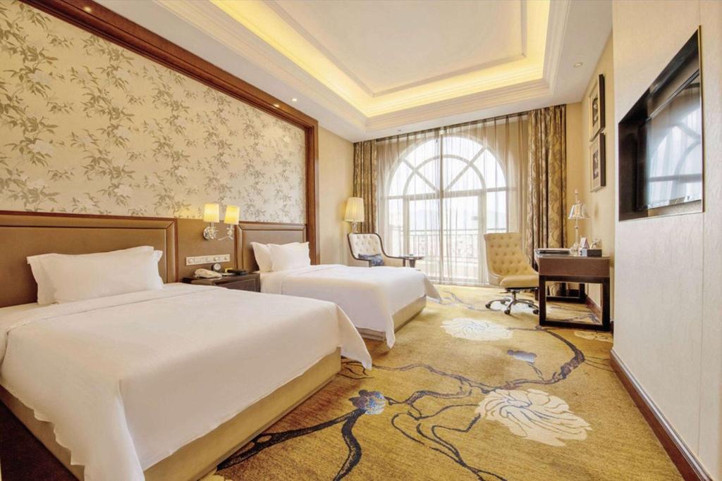 恵州市にあるDays Hotel Logan City Huizhouのベッド2台とデスクが備わるホテルルームです。