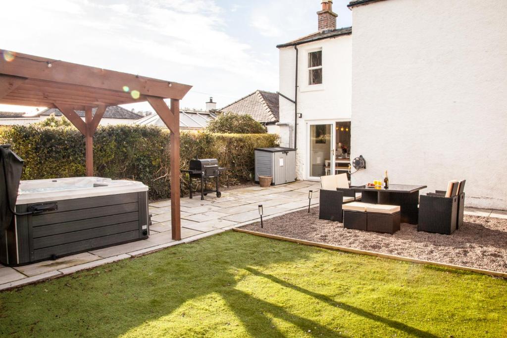 een achtertuin met een patio met een tafel en een grill bij Luxury Scottish Hot Tub Getaway in Gatehouse of Fleet