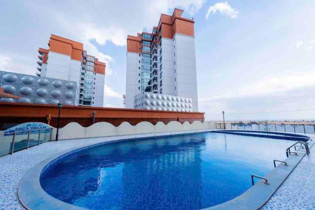 una piscina en la azotea de un edificio con edificios altos en Abantu Parkview 2BR Suite near JKIA SGR with Pool Gym Eatery en Nairobi