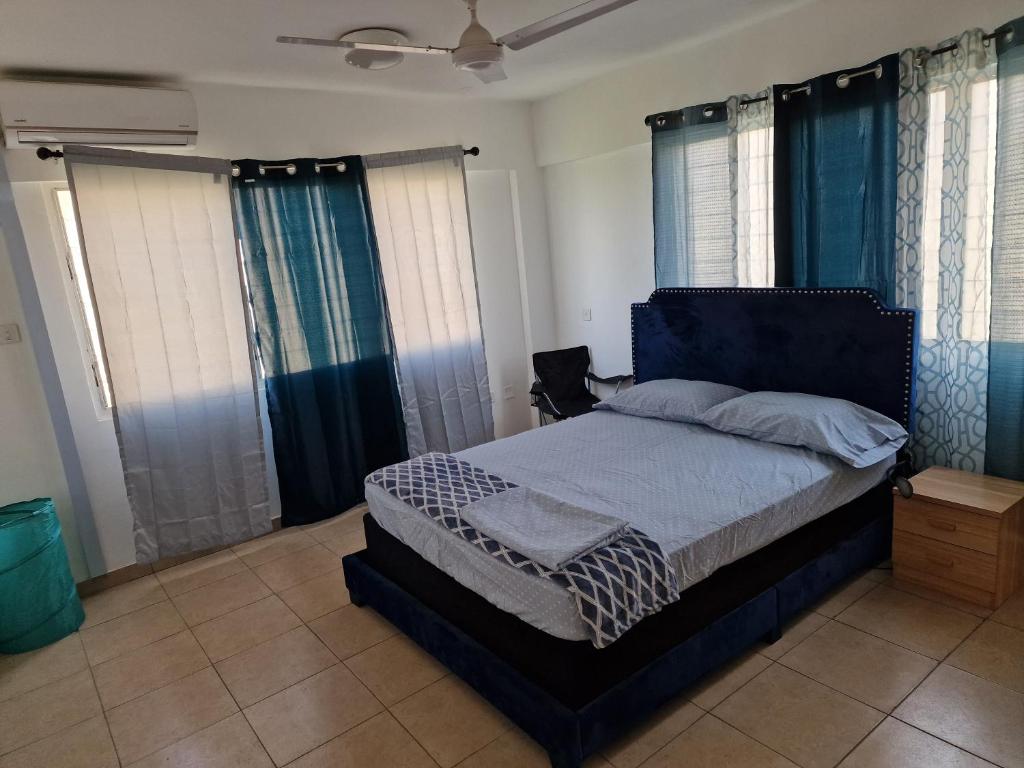 a bedroom with a large bed with blue curtains at Sigma Theta Homes - KNUST Area in Kumasi