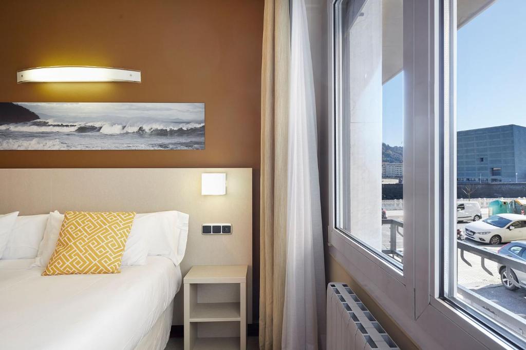 a bedroom with a bed and a large window at Hotel Parma in San Sebastián