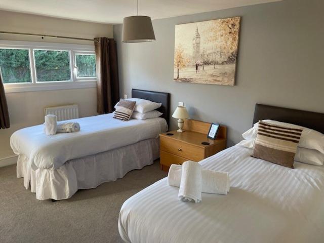 1 dormitorio con 2 camas con sábanas blancas en Chequers Country Inn, en Lutterworth
