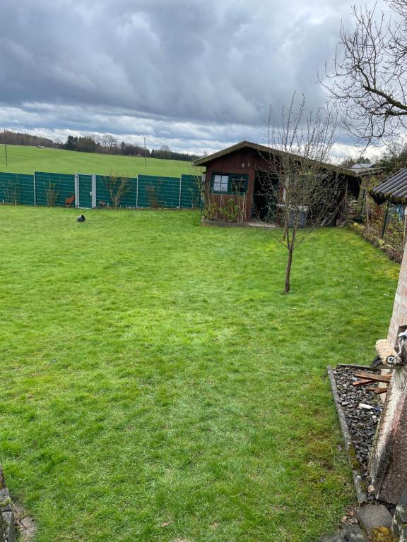 um quintal com uma casa e um campo verde em Widmanns Ferienquartier em Wiehl