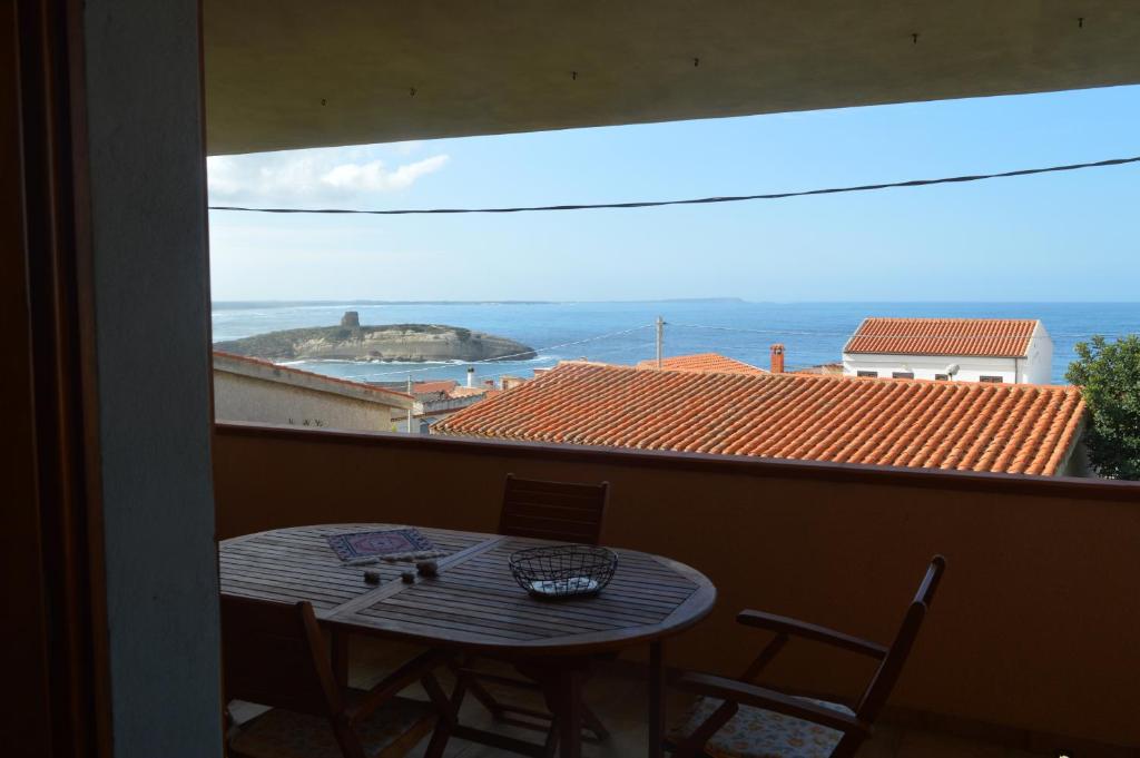 een tafel en stoelen op een balkon met uitzicht op de oceaan bij Casa del Cisto in S'archittu Cuglieri