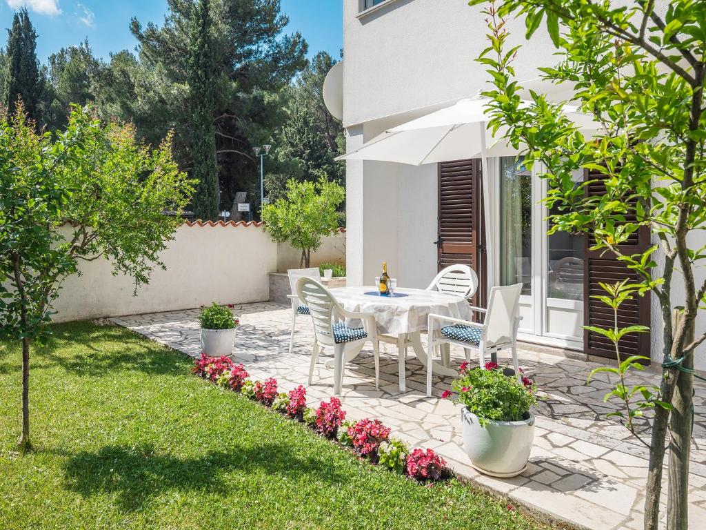 d'une terrasse avec une table blanche, des chaises et des fleurs. dans l'établissement Apartment Gloria Premium, à Poreč