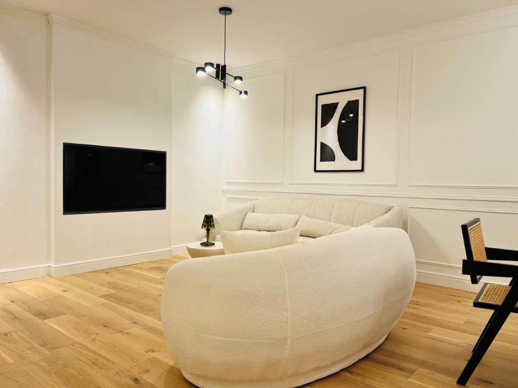 a living room with a white couch and a tv at Le Kronenbourg - À deux arrêts de tram du centre-ville in Strasbourg