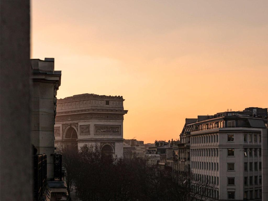 une ligne d'horizon avec des bâtiments et un coucher de soleil dans l'établissement Hôtel Le Royal Monceau Raffles Paris, à Paris