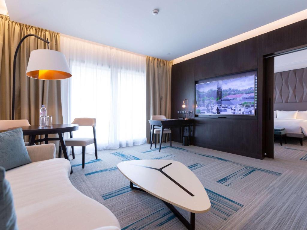 a living room with a couch and a tv at Novotel Convention And Spa in Antananarivo