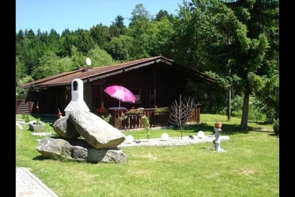 une maison avec un parapluie rose et un rocher dans l'établissement Ferienhaus für 4 Personen ca 45 qm in Eppenschlag, Bayern Bayerischer Wald, à Eppenschlag