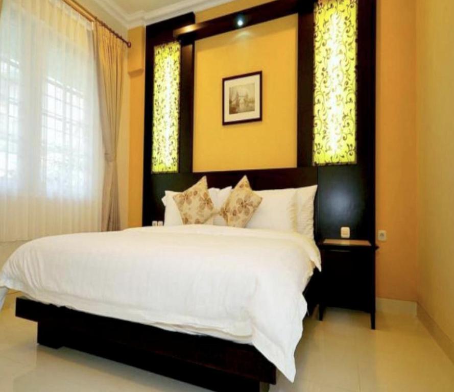 a bedroom with a large white bed and two windows at Cove Ottenville Boutique Hotel in Bandung