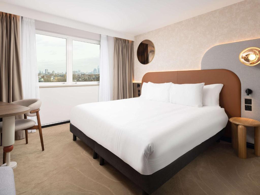 a hotel room with a white bed and a window at Mercure London Earls Court in London