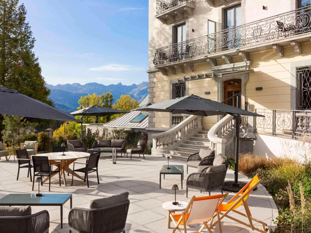 聖熱爾韋萊班的住宿－Le Saint Gervais Hotel & Spa Handwritten Collection，大楼前方的带桌椅和遮阳伞的天井。
