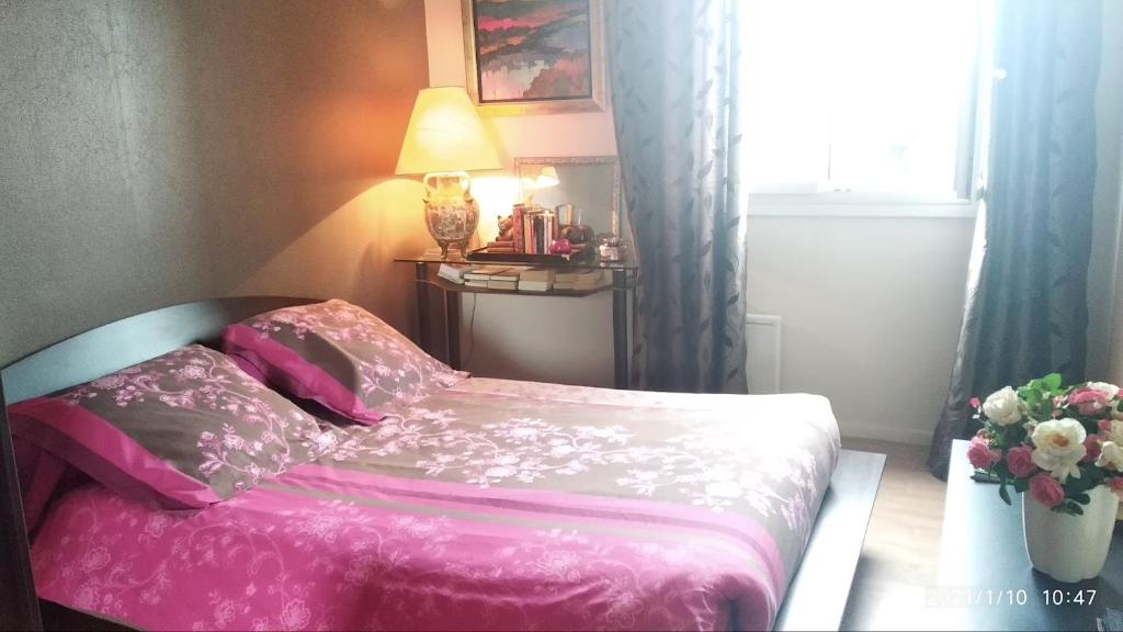 Un dormitorio con una cama rosa y un jarrón de flores en Chambre Rafaël chez particulier en Cherburgo