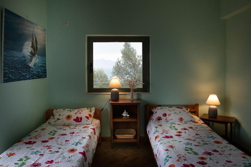 een slaapkamer met 2 bedden en een raam bij Tritsili house in Koroni