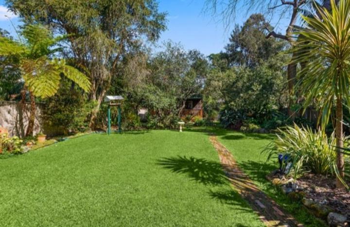 einen Garten mit grünem Rasen mit Bäumen und Sträuchern in der Unterkunft Koloona in Wollongong