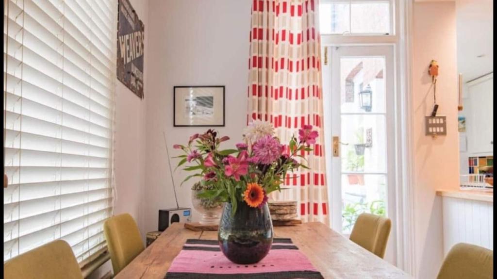 una mesa de comedor con un jarrón de flores. en Maple Cottage, Canterbury - Little City Gem en Canterbury