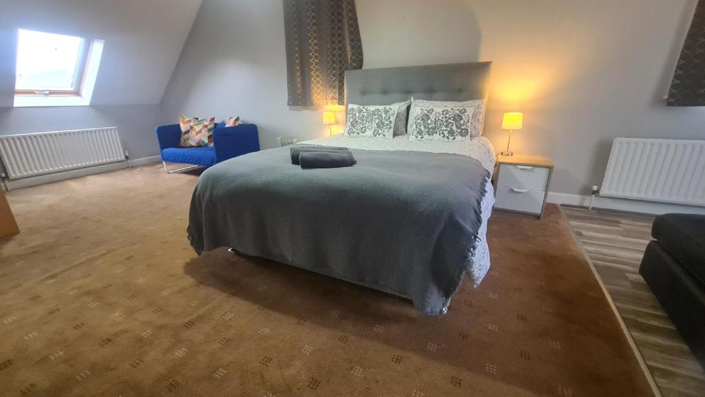 um quarto com uma cama grande e uma cadeira azul em Alexandra Park Town House 223 em Belfast